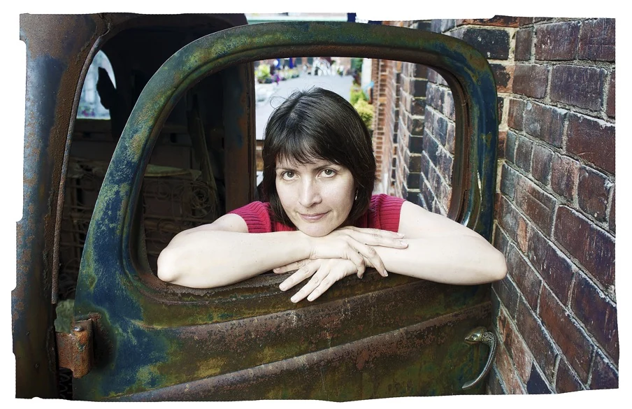 Maria Drazilov leaning on the door of a vintage vehicle